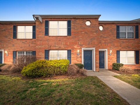 the front of a brick house with blue doors and windows